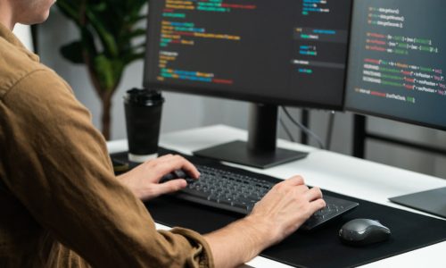 IT developer working online software development on pc monitors at modern home office on coding application screens, creating updated latest program firmware information version concept. Gusher.